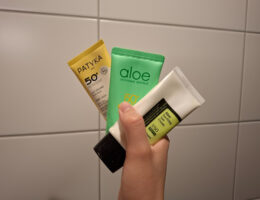 Kolme aurinkovoidetuubia kädessä